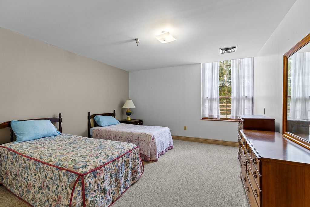 Bedroom with two twin beds, a dresser, and a window with white curtains.