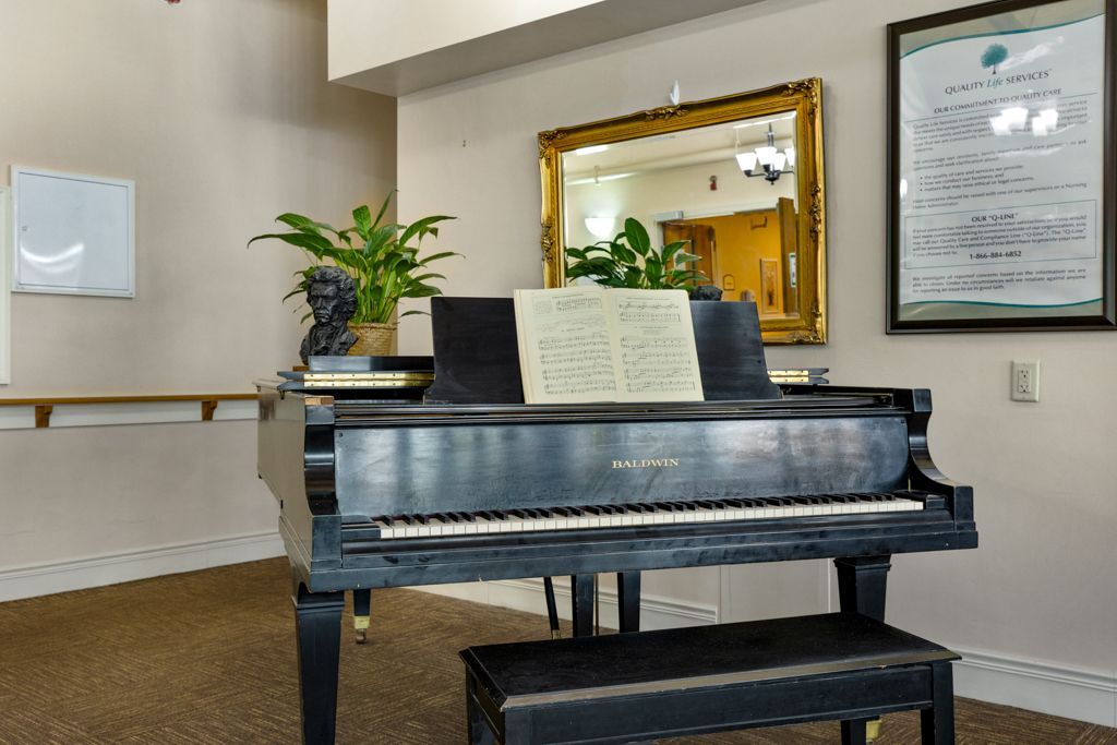 A grand piano with sheet music in a room with a mirror and potted plants.