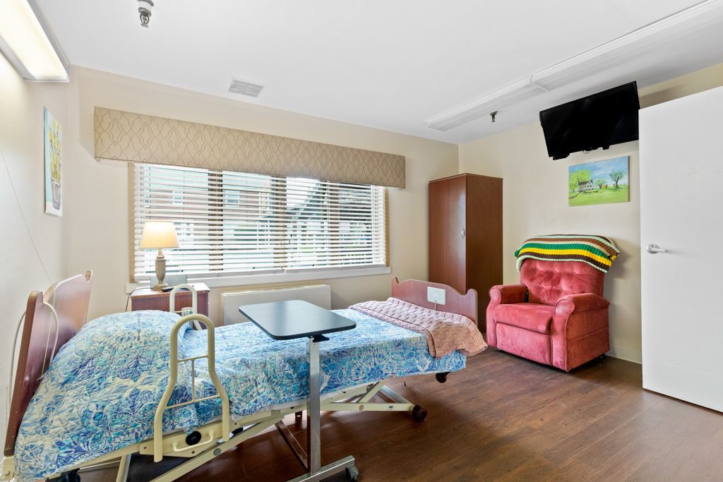 Hospital room with a bed, recliner, and small TV mounted on wall.