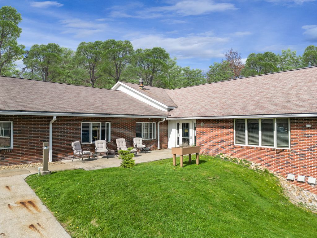 Brick building with patio, chairs, and green lawn under blue sky.