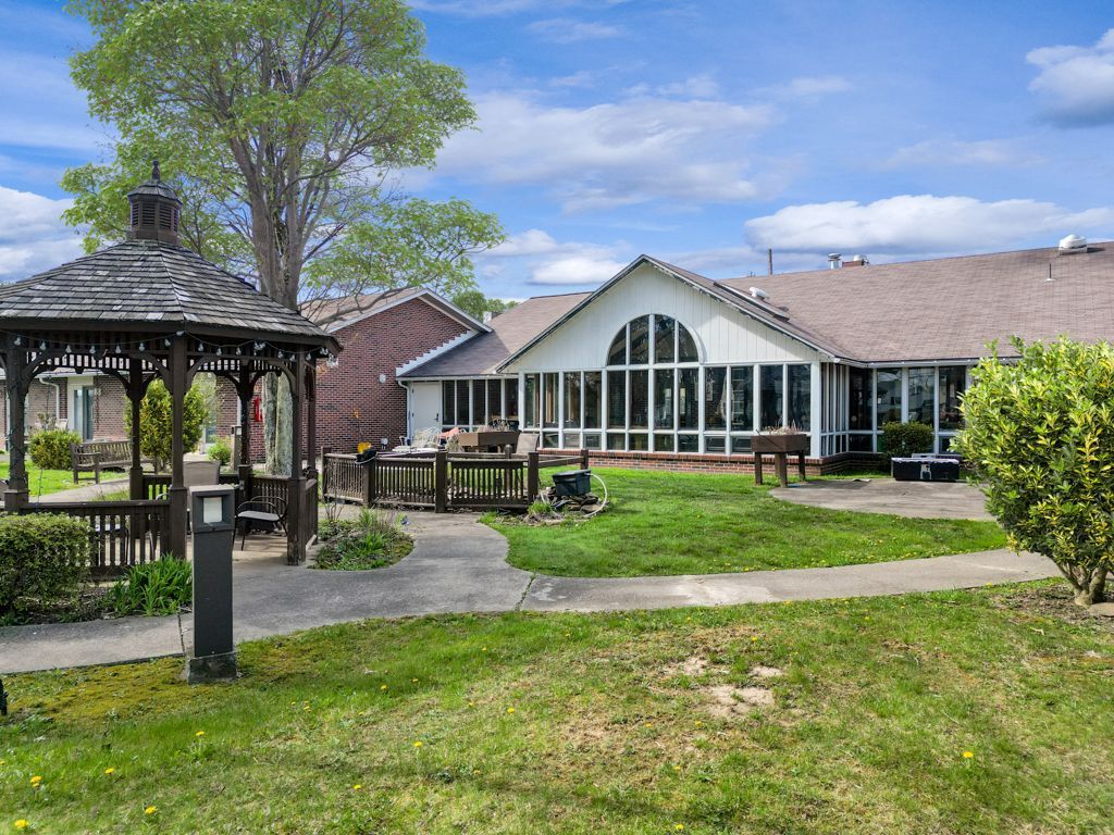Lush green yard with gazebo and building; partially cloudy sky.