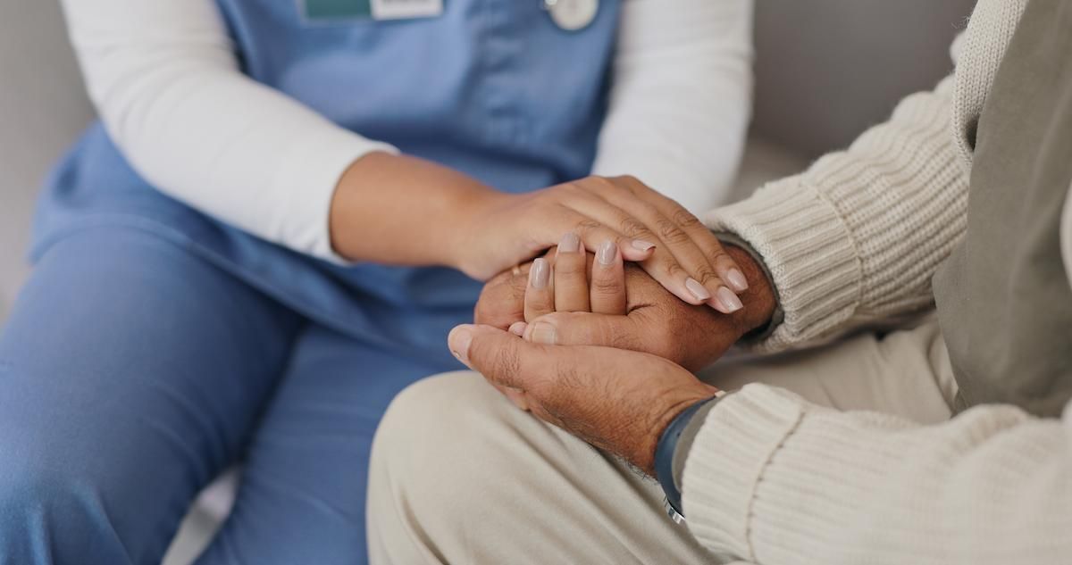 Closeup of a caregiver holding hands with a client 
