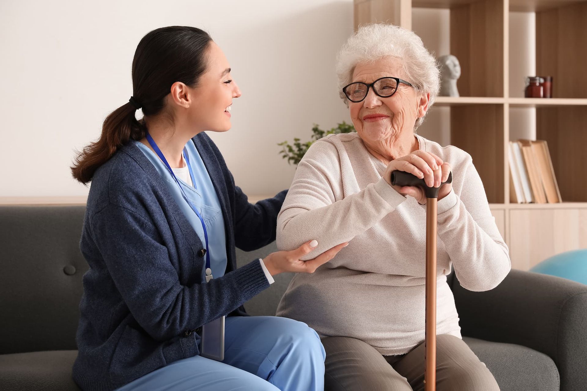 home health aide from Quality Life Services chats warmly with elderly patient holding cane