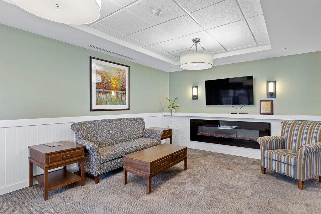 Living room with green walls, couches, TV, and artwork.