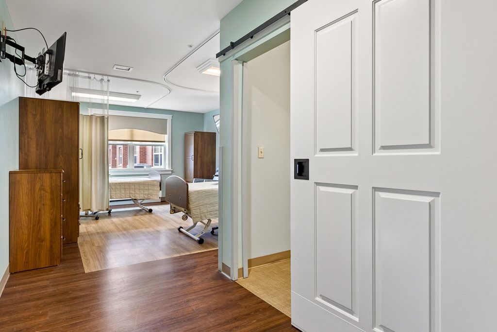 Assisted Living interior with a sliding door, wooden floor, and medical equipment.
