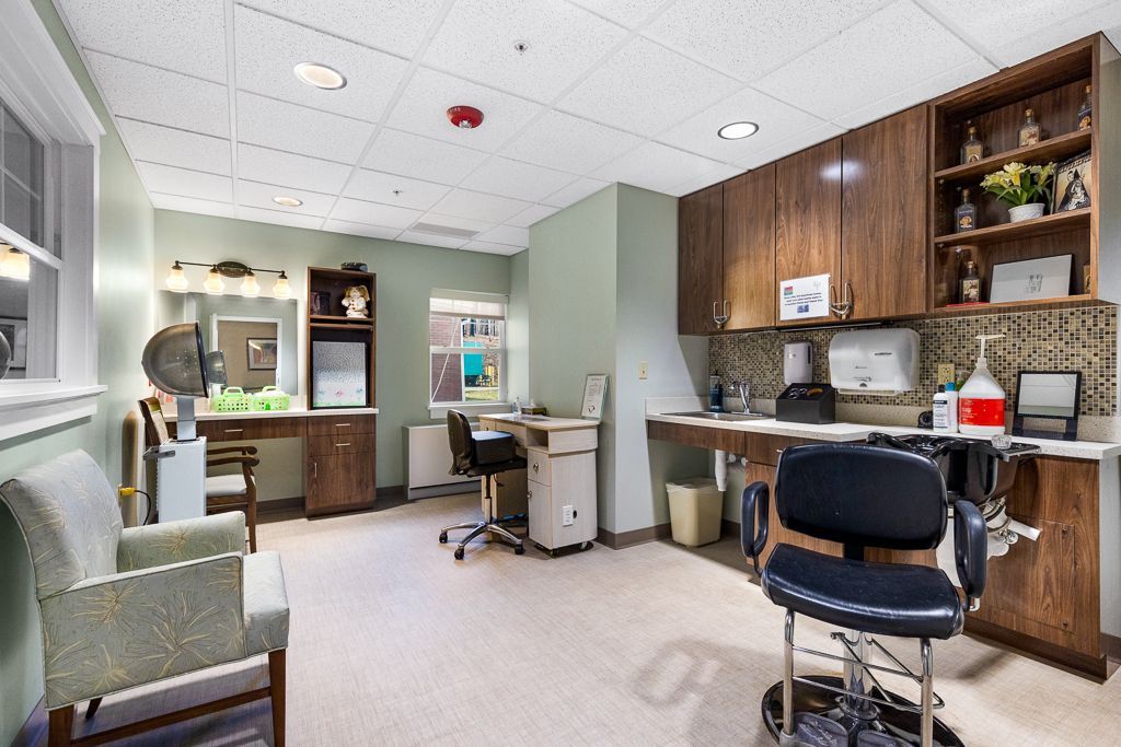 Hair salon interior with a styling chair, cabinets, and a vanity station.