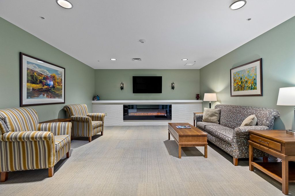 Living room with armchairs, sofa, fireplace, and TV against a green-painted wall.