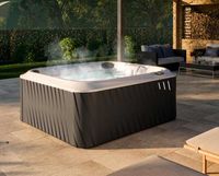 Outdoor hot tub with steaming water on a stone patio in a modern backyard