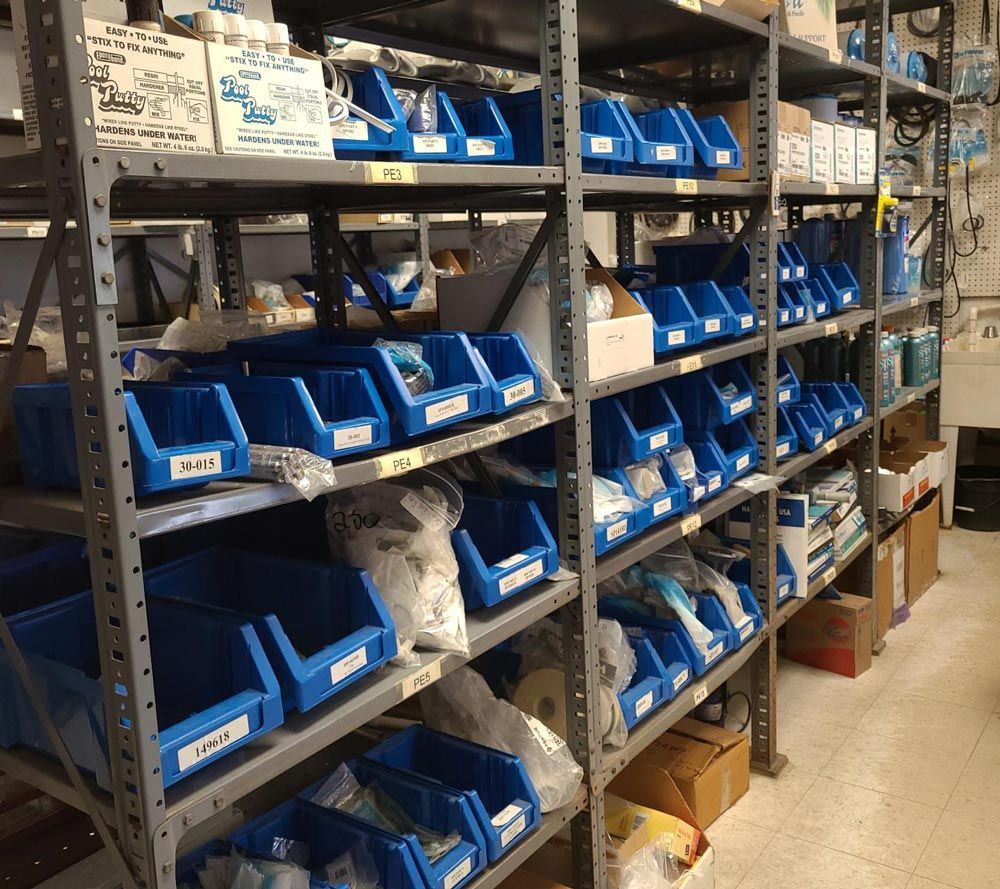 Warehouse shelves lined with blue storage bins and labeled boxes in a stockroom