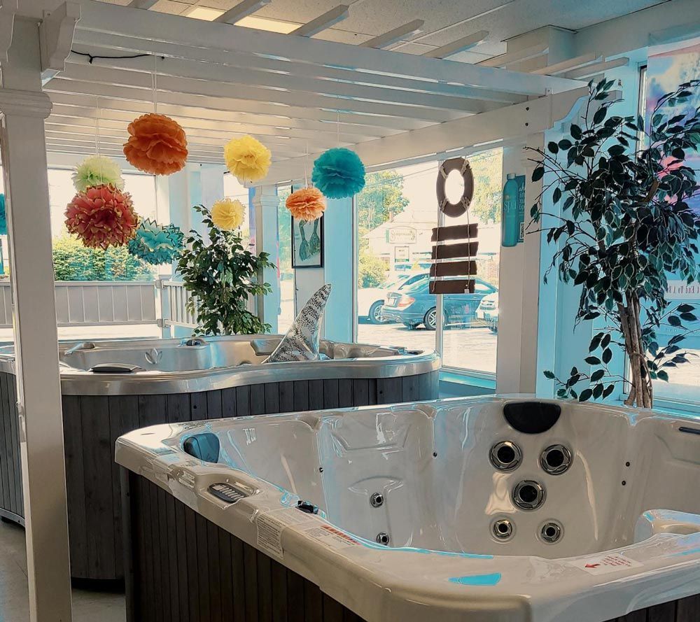 Bright spa showroom with a white hot tub, hanging paper lanterns, and large windows.