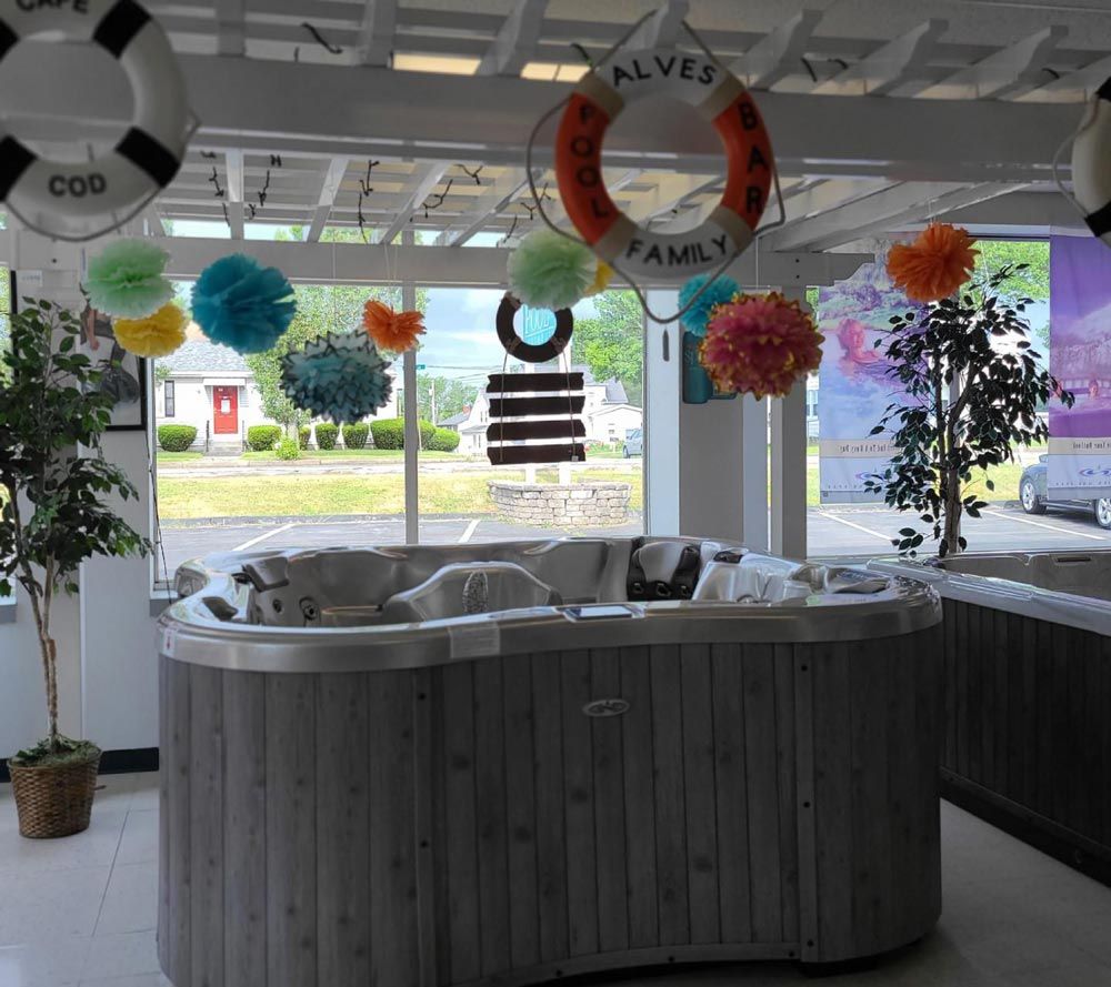 Hot tub display in a bright showroom with colorful hanging decorations and life rings above the windows