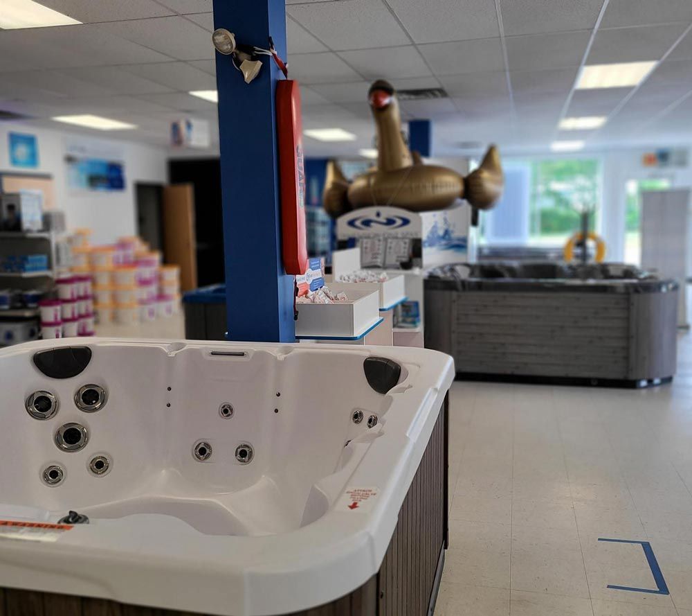 White hot tub in a showroom with hanging gold inflatable ducks and furniture in the background
