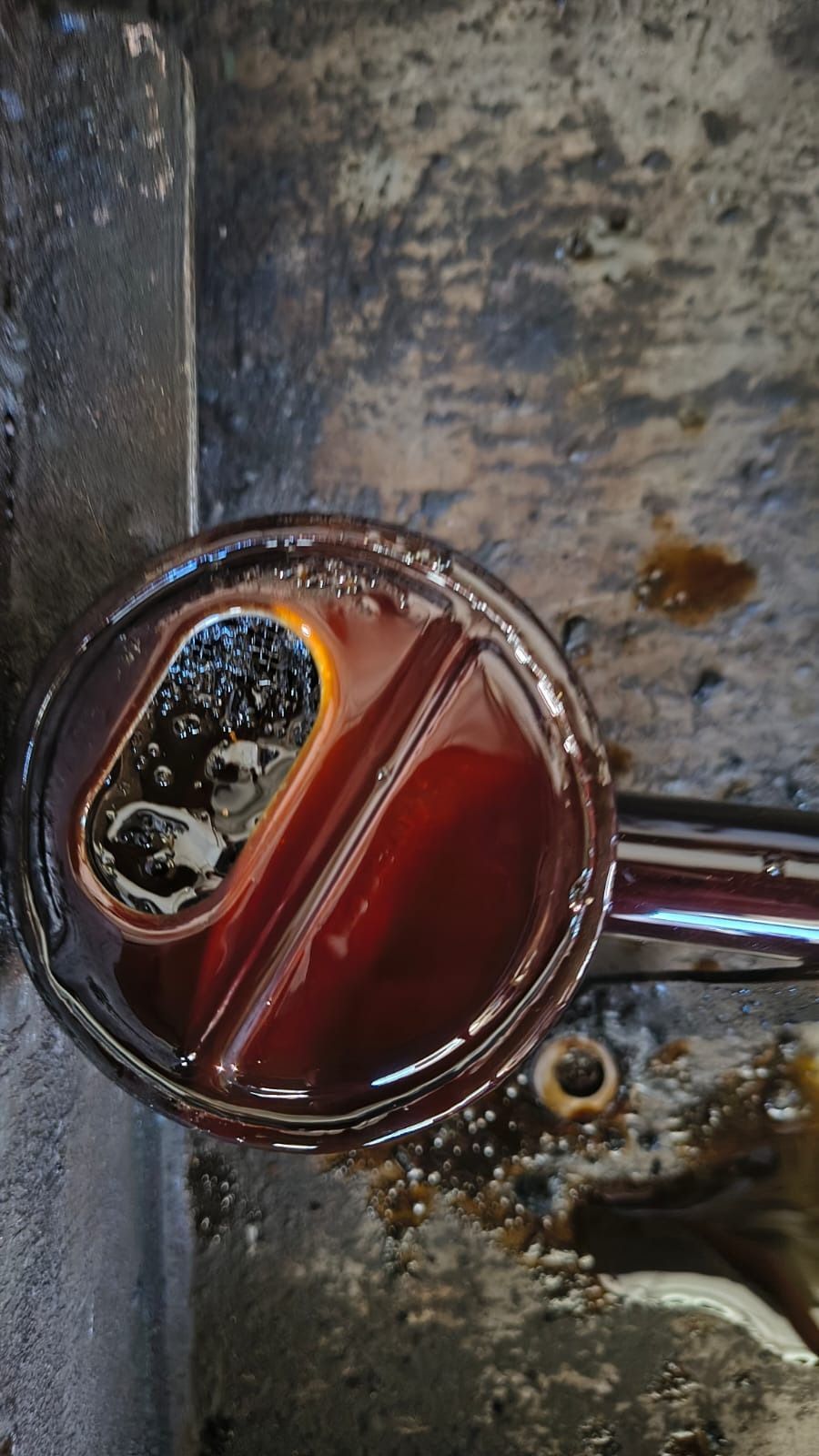 Sartén roja sucia con mango de cuchara, vista desde arriba.