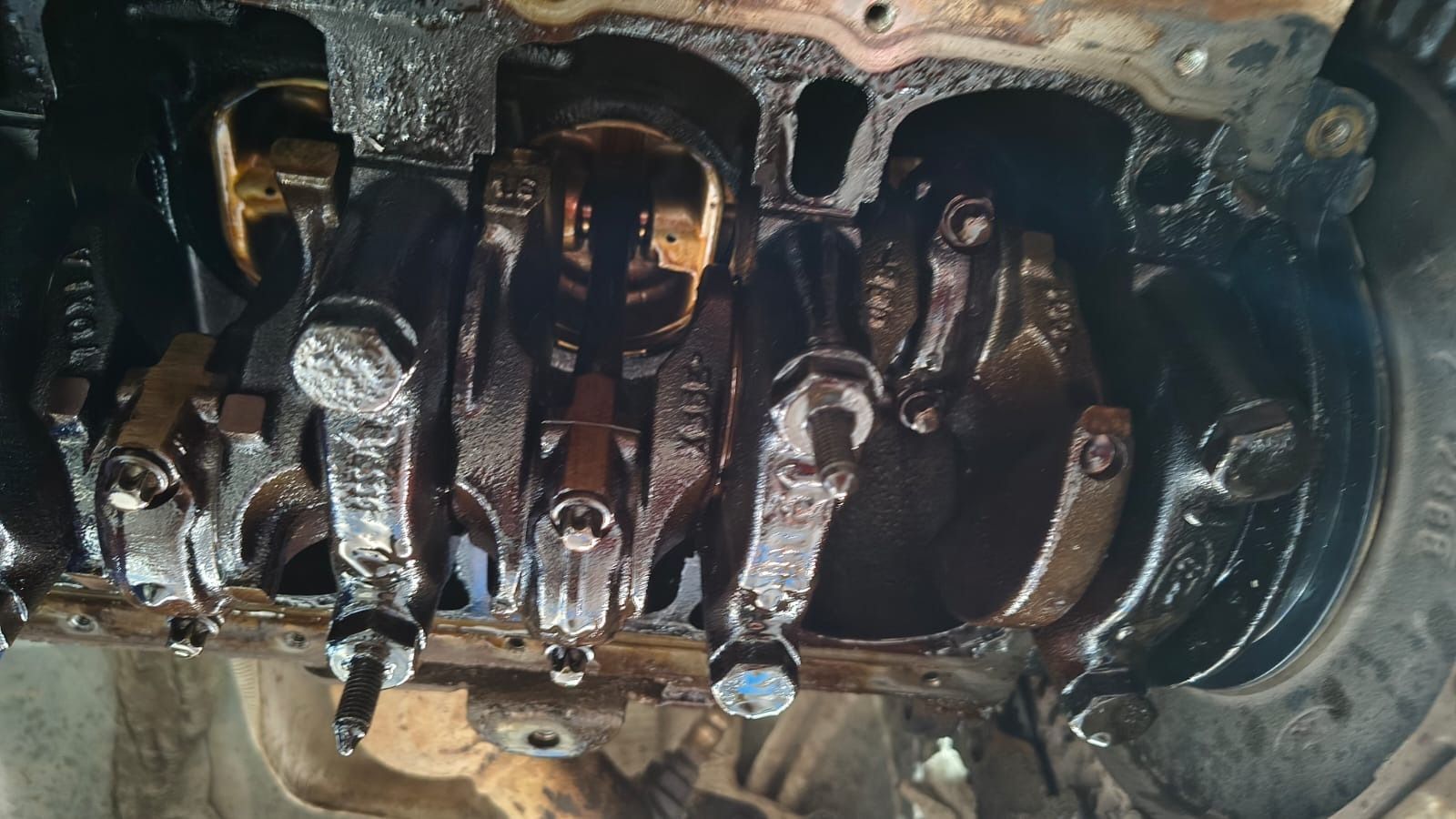 Cigüeñal y bielas oxidados al descubierto en el bloque motor de un vehículo desmontado.