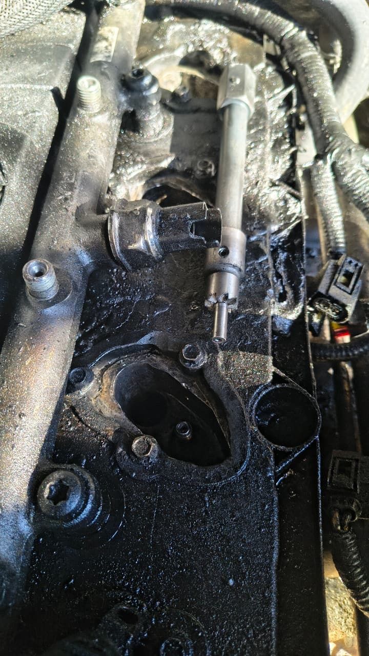 Primer plano de un motor de coche sucio con residuos de aceite/grasa y mangueras y cableado visibles.
