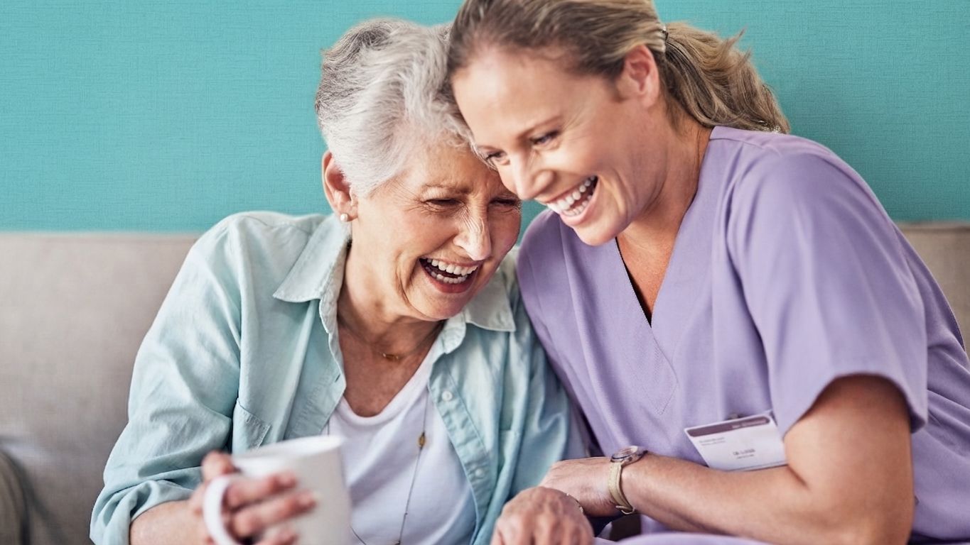 Caretaker helping an elderly man with a walker in a bright room