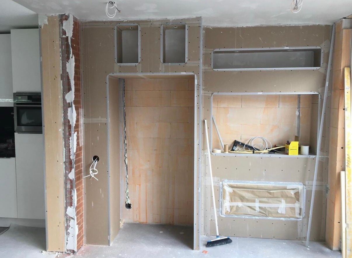 Onafgewerkte kamer met zichtbare gipsplaten, open kast en ingebouwde planken, momenteel in renovatie.
