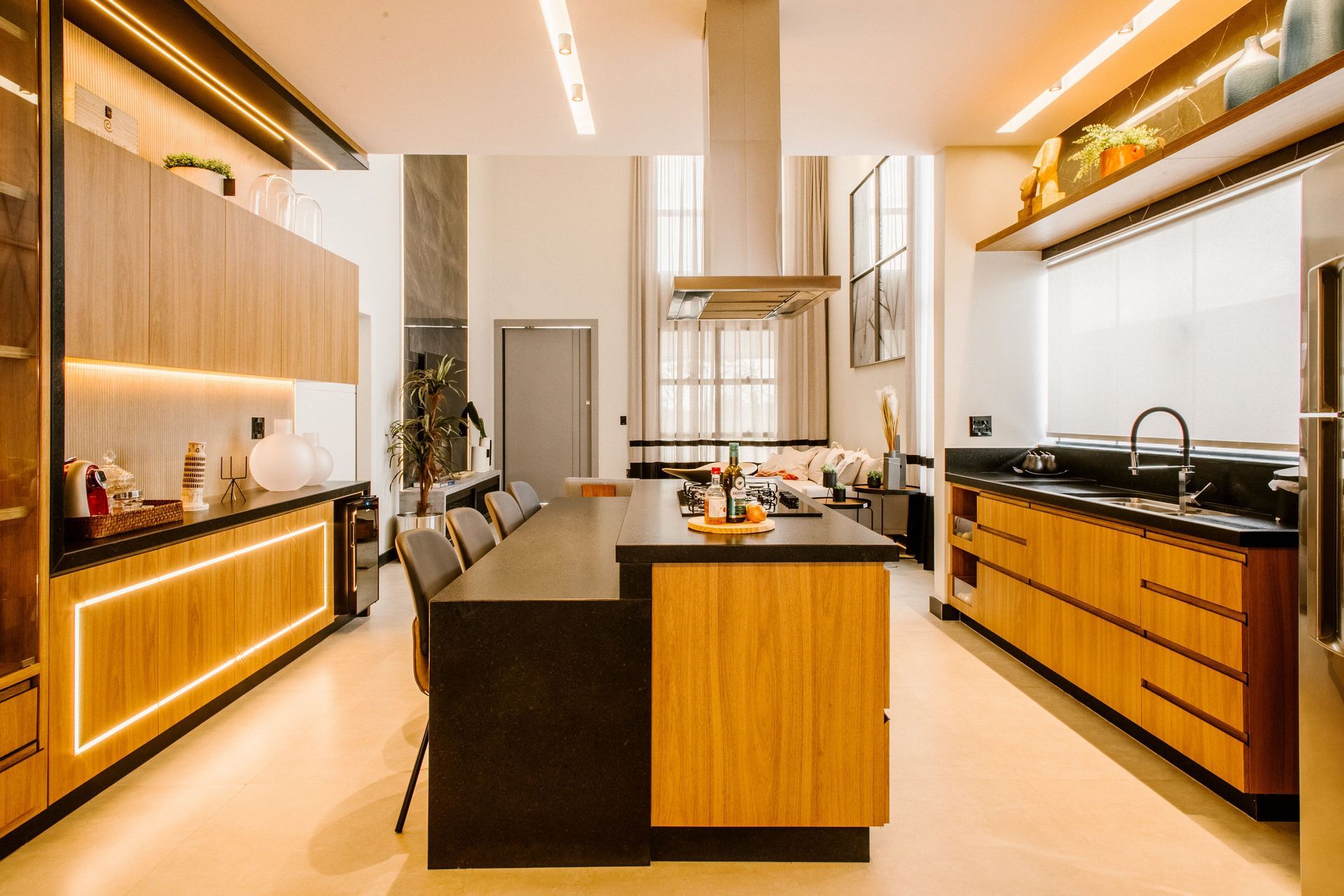 Moderne keuken met houten kasten, zwarte werkbladen en een kookeiland onder warme verlichting.