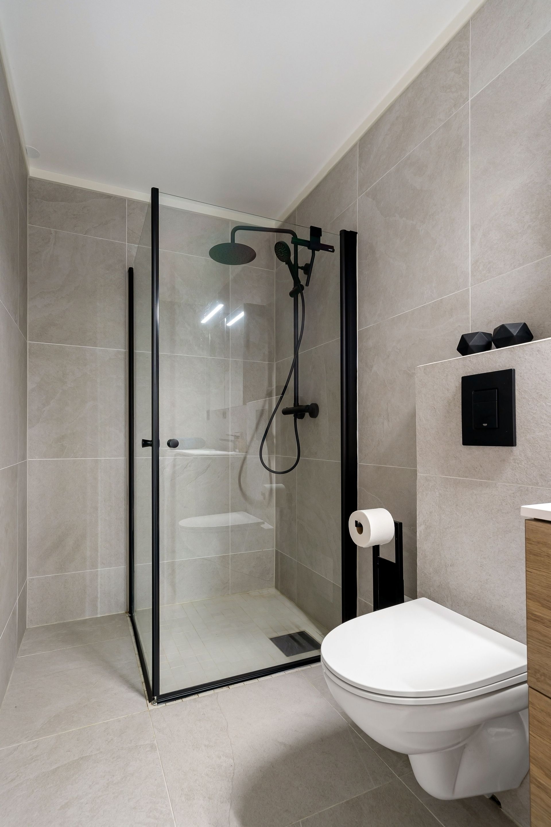 Moderne badkamer met glazen douchecabine, wandtoilet en beige betegelde wanden.