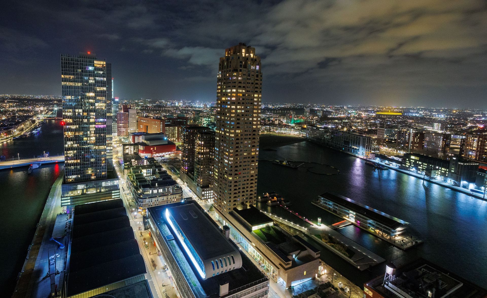 De skyline van de stad 's nachts met verlichte wolkenkrabbers en de weerspiegeling van de rivier.