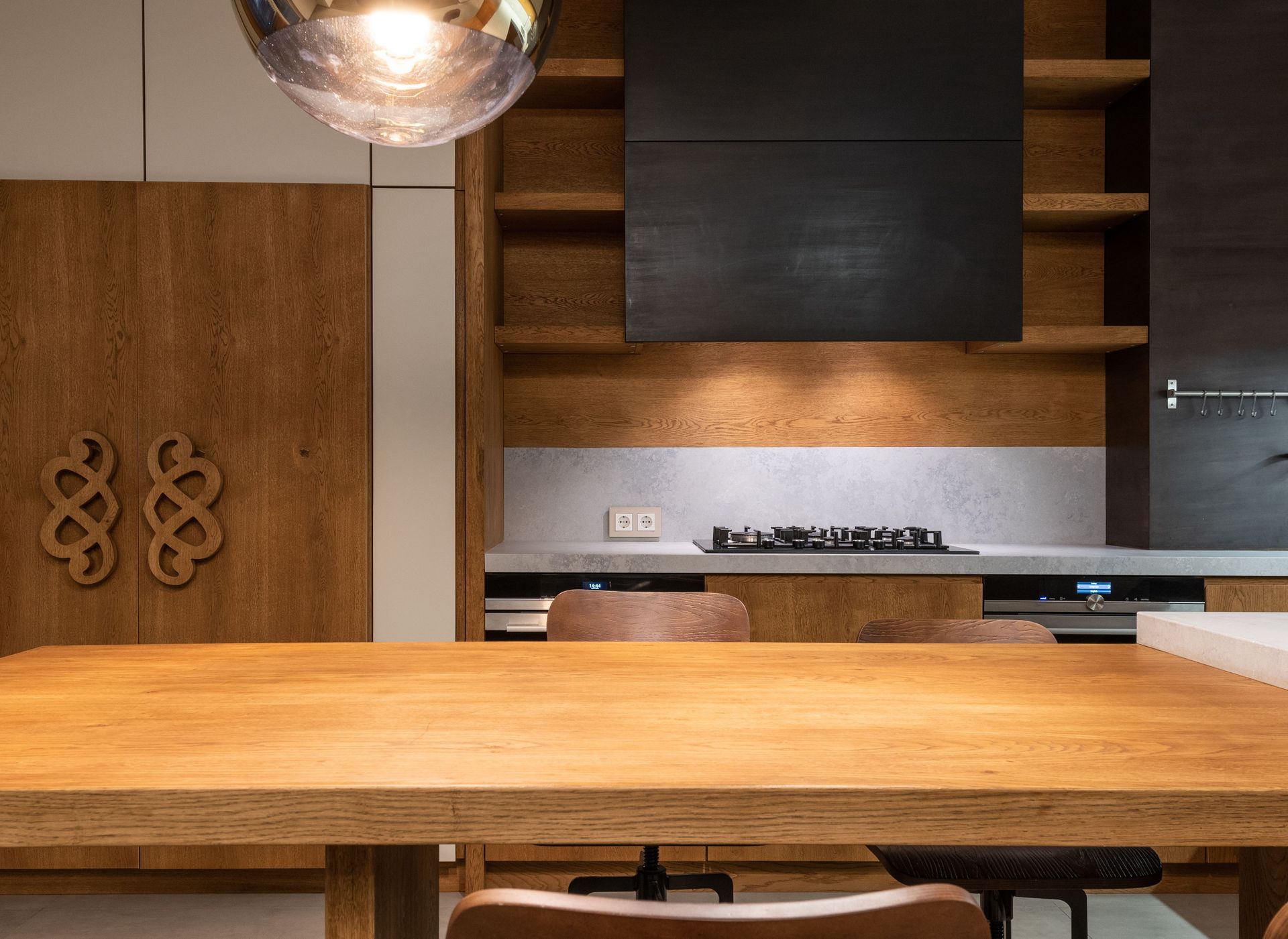 Moderne keuken met houten kookeiland, ingebouwde oven en warme houten kasten in een eigentijds interieur.