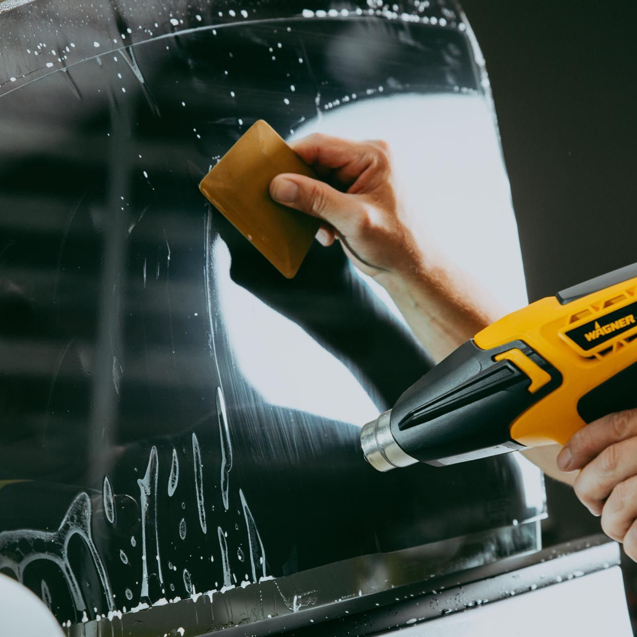 Technician installing a car door panel in a workshop, adjusting a black interior trim piece.