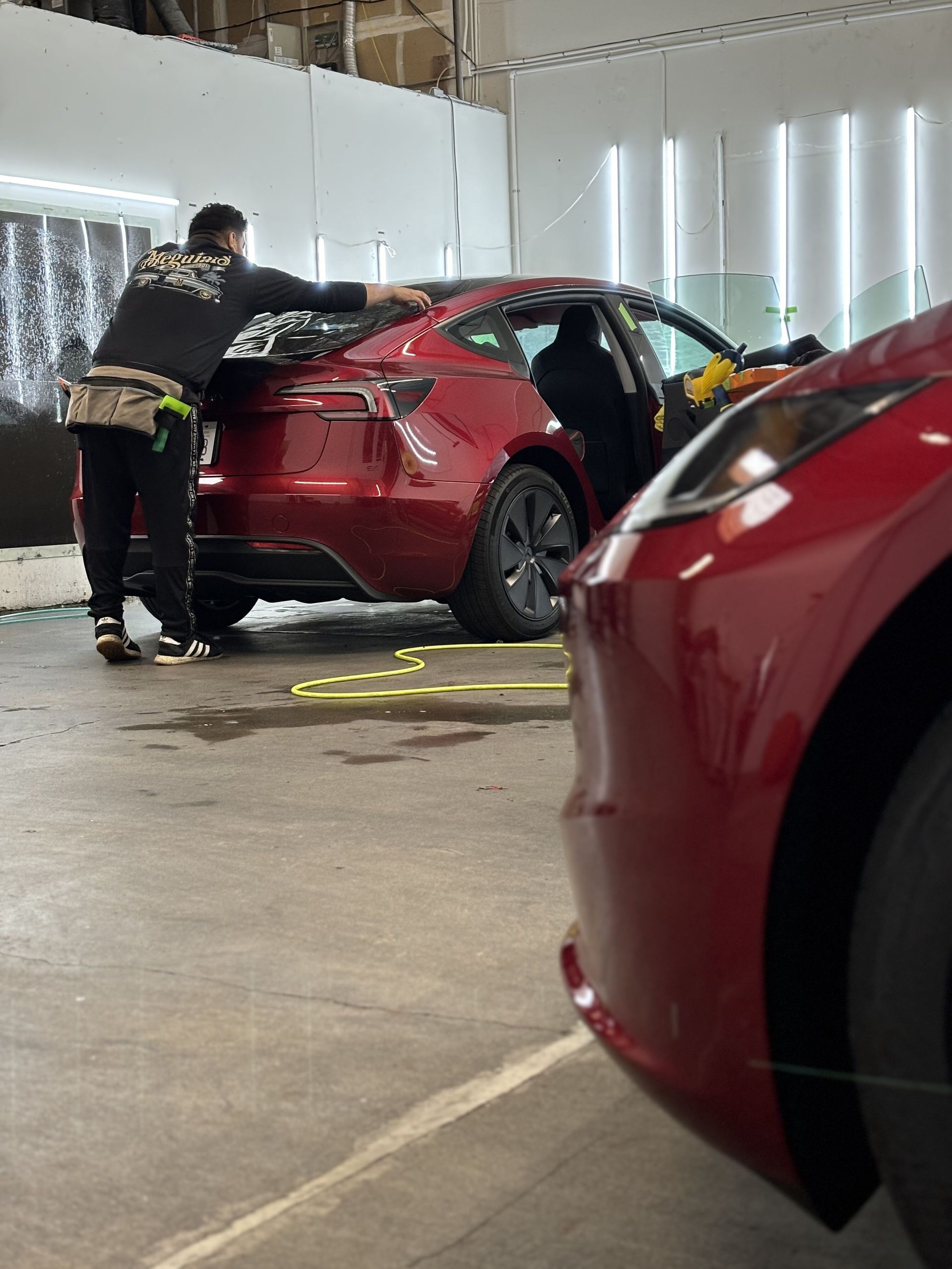 Person pushing a red car in a parking garage, with a red car blurred in the foreground.
