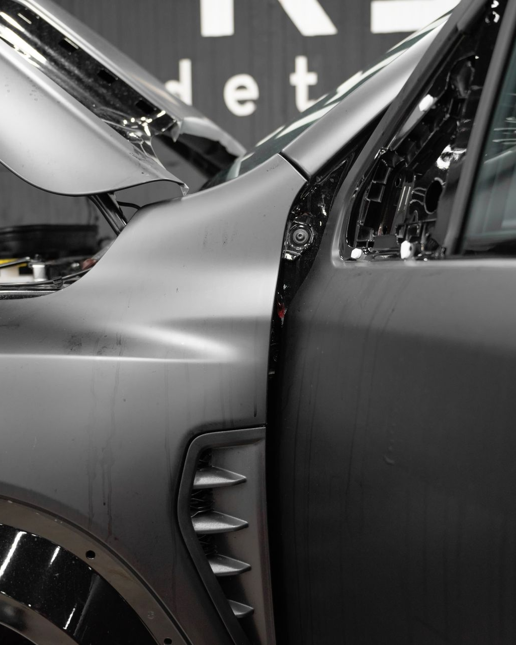 Close-up of a silver car’s front side with the door open, showing the wheel and vent details.