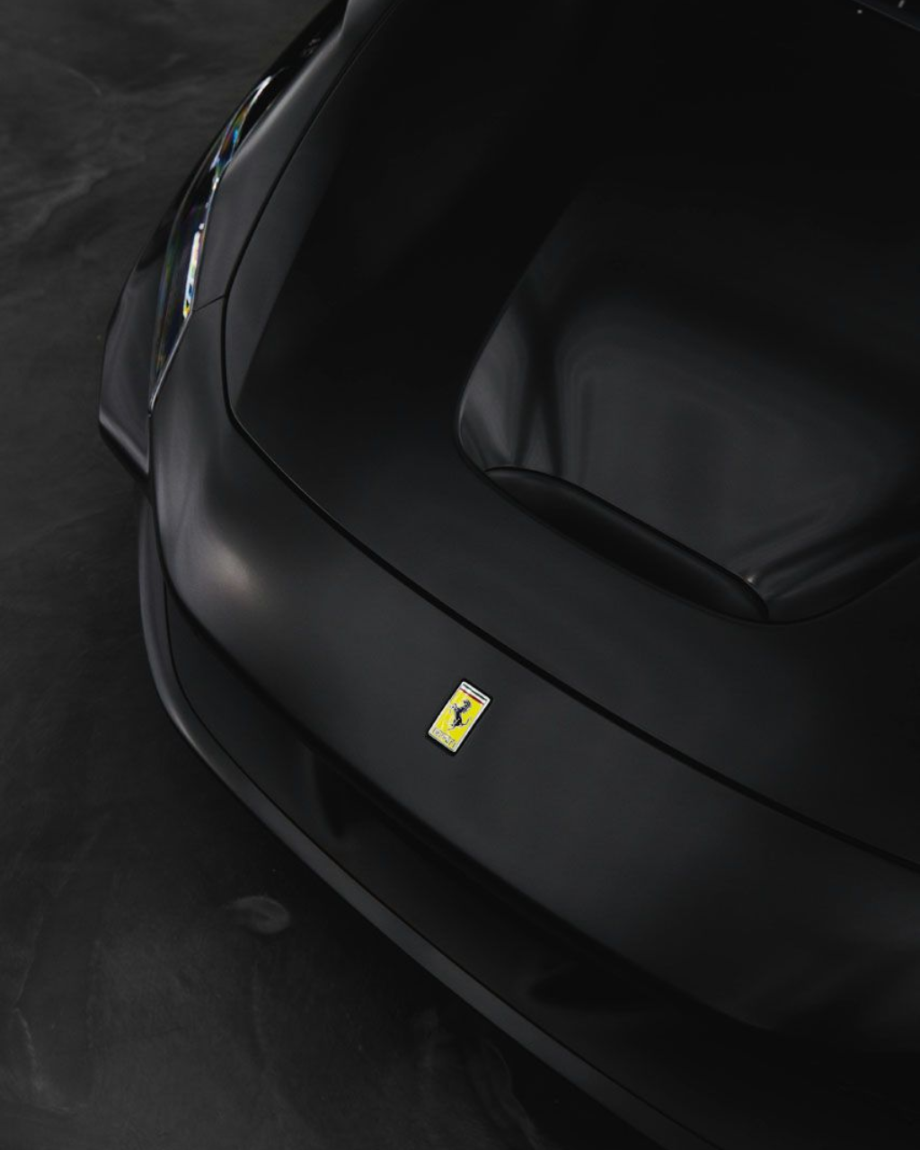 Close-up of a black Ferrari car front with the yellow prancing horse emblem.
