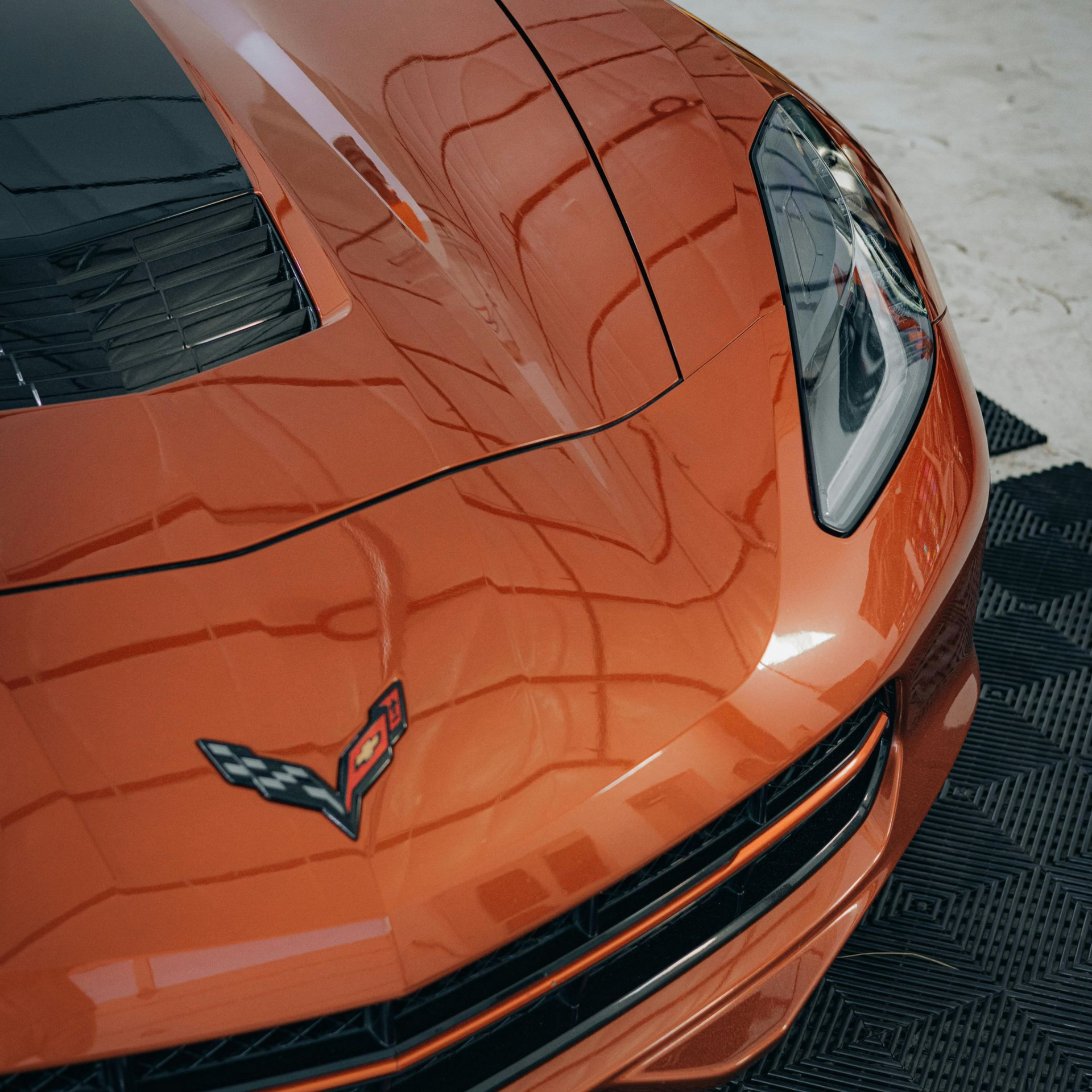 Orange Chevrolet Corvette sports car viewed from above in a showroom setting