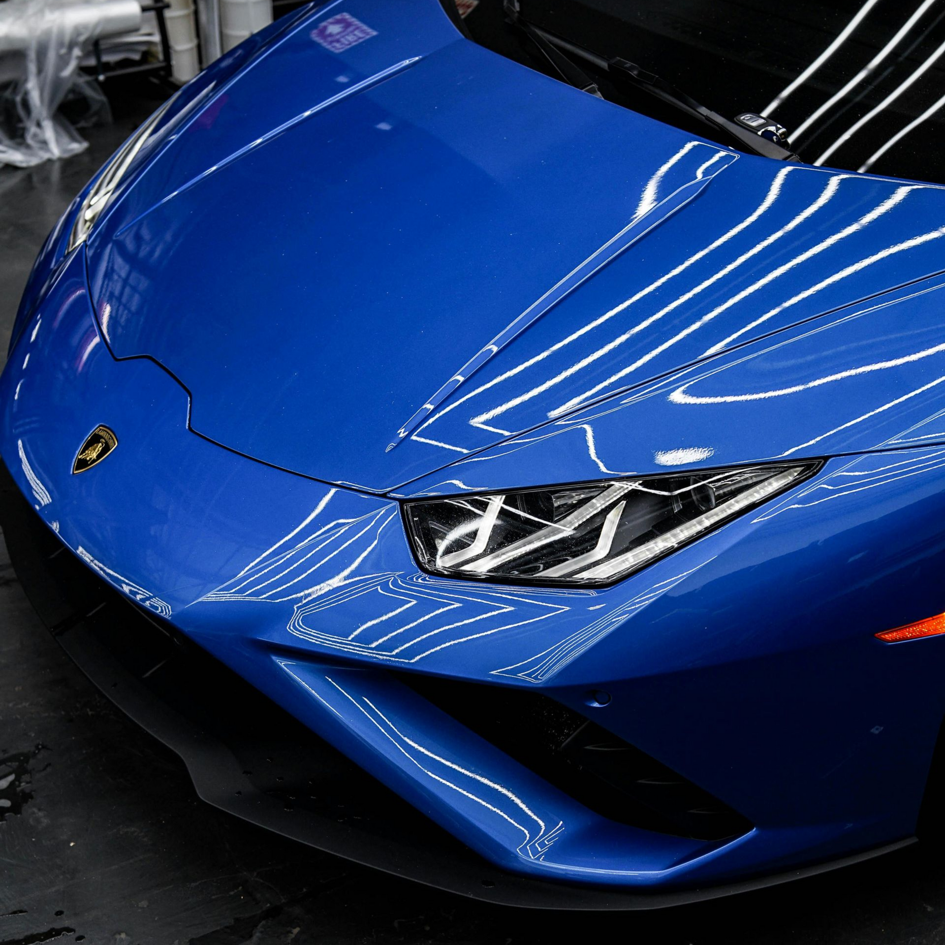 Blue Lamborghini sports car front view in a showroom, with sleek headlights and reflective paint.
