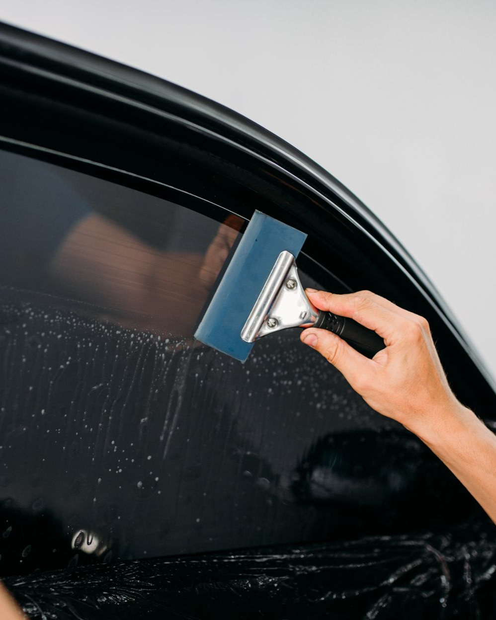 Person polishing a red car headlight with a cloth and tool during auto detailing