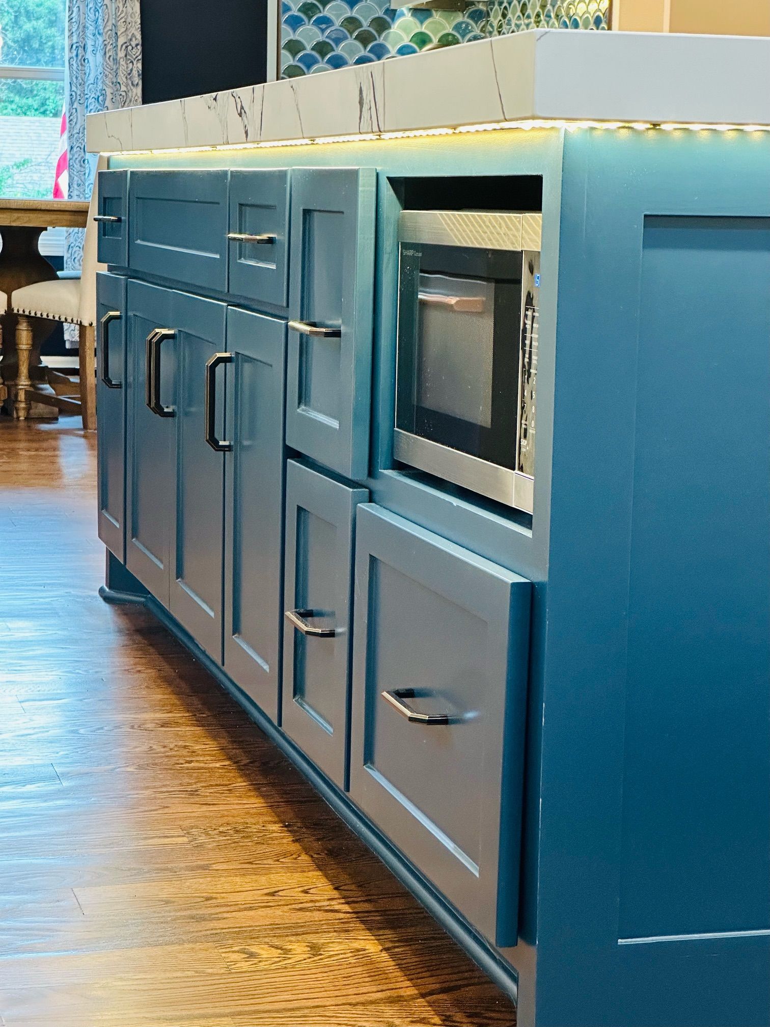 A kitchen with blue cabinets and a microwave
