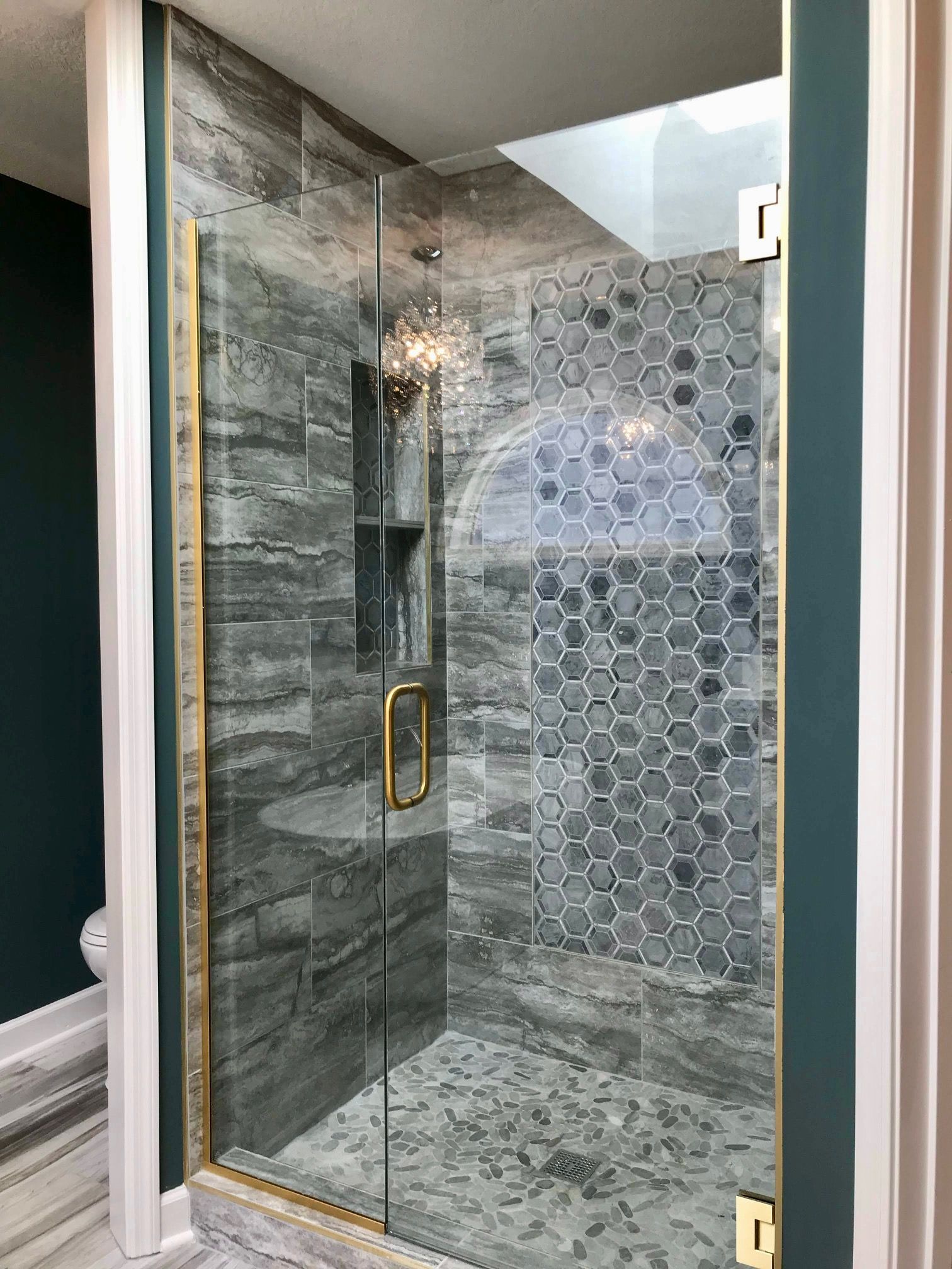 A bathroom with a walk in shower with a glass door.