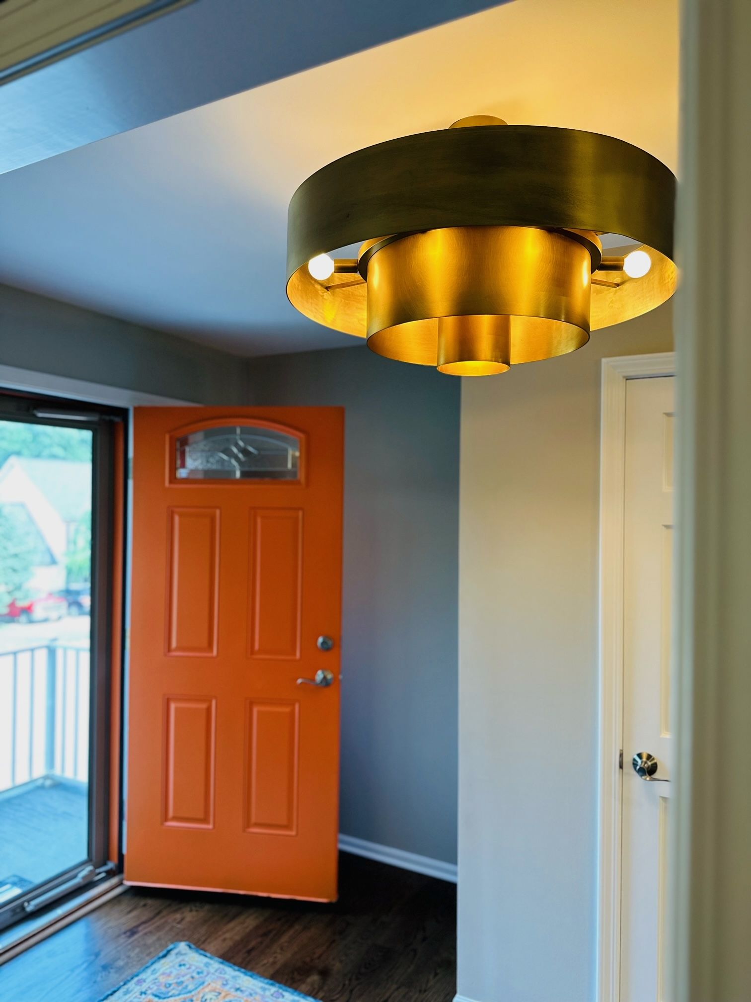 A hallway with an orange door and a ceiling light