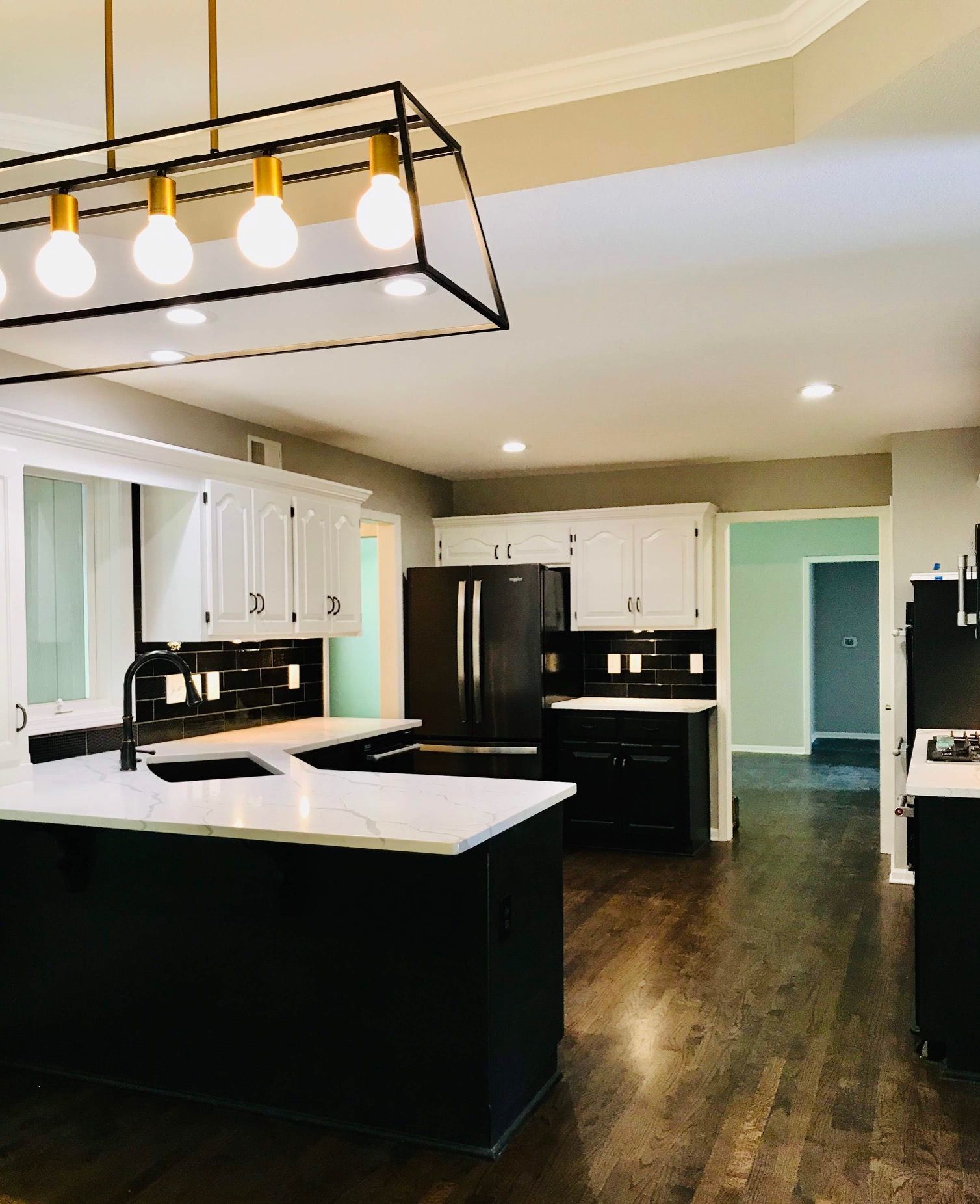 A kitchen with white cabinets and a black refrigerator