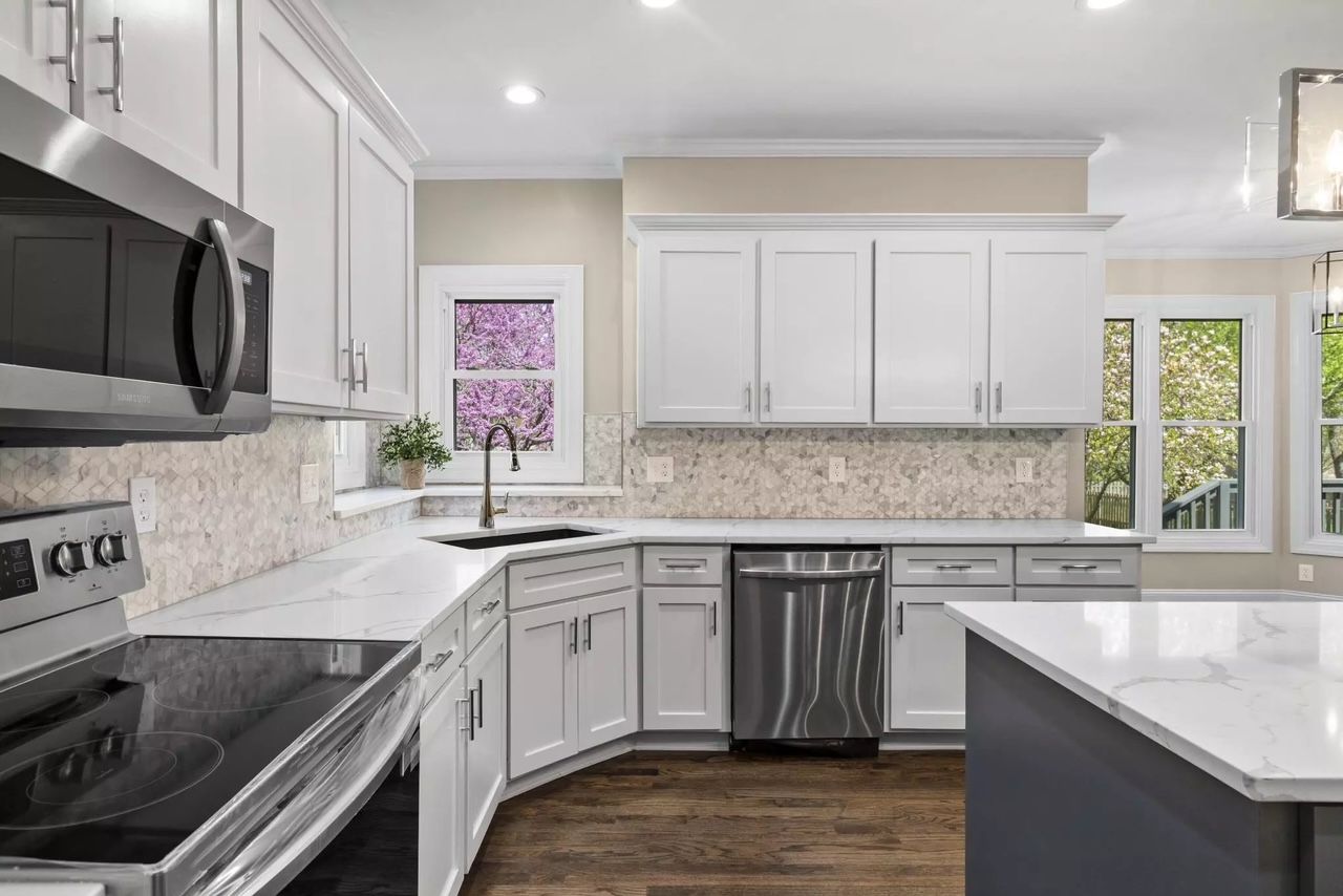 A kitchen with white cabinets , stainless steel appliances , and a large island.