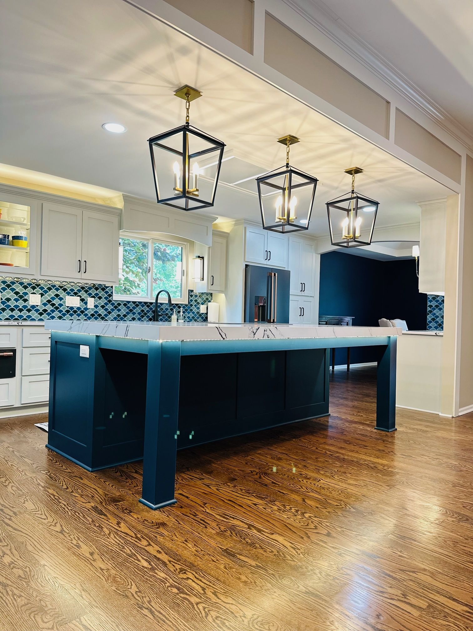 A kitchen with a large island and lanterns hanging from the ceiling.