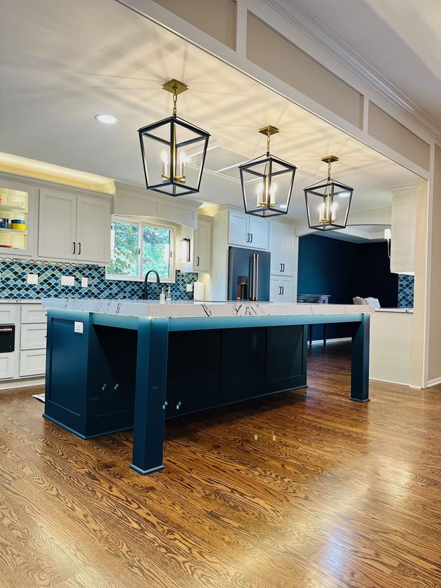 A kitchen with a large island and lanterns hanging from the ceiling.