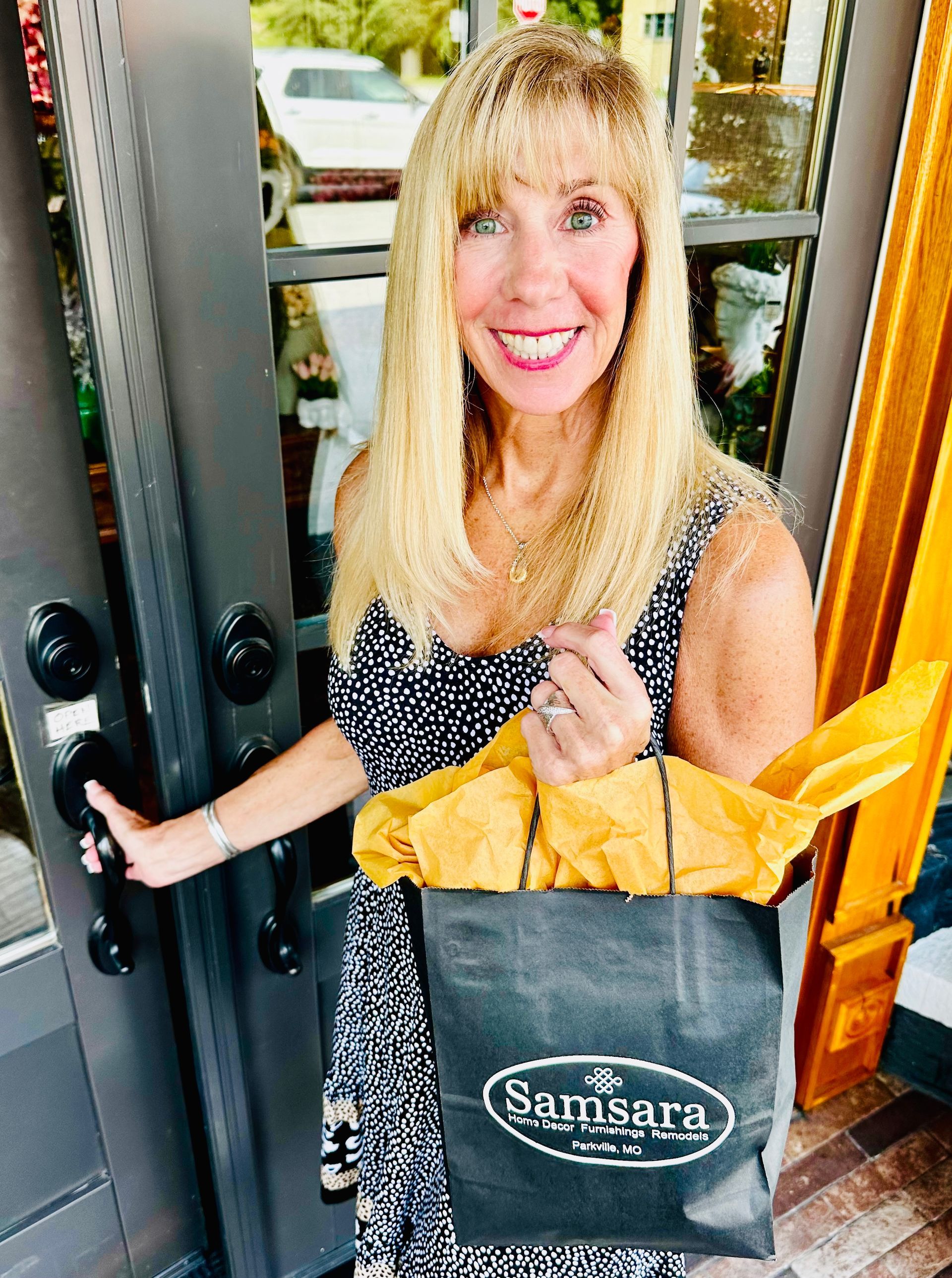 A woman is holding a shopping bag in front of a door.
