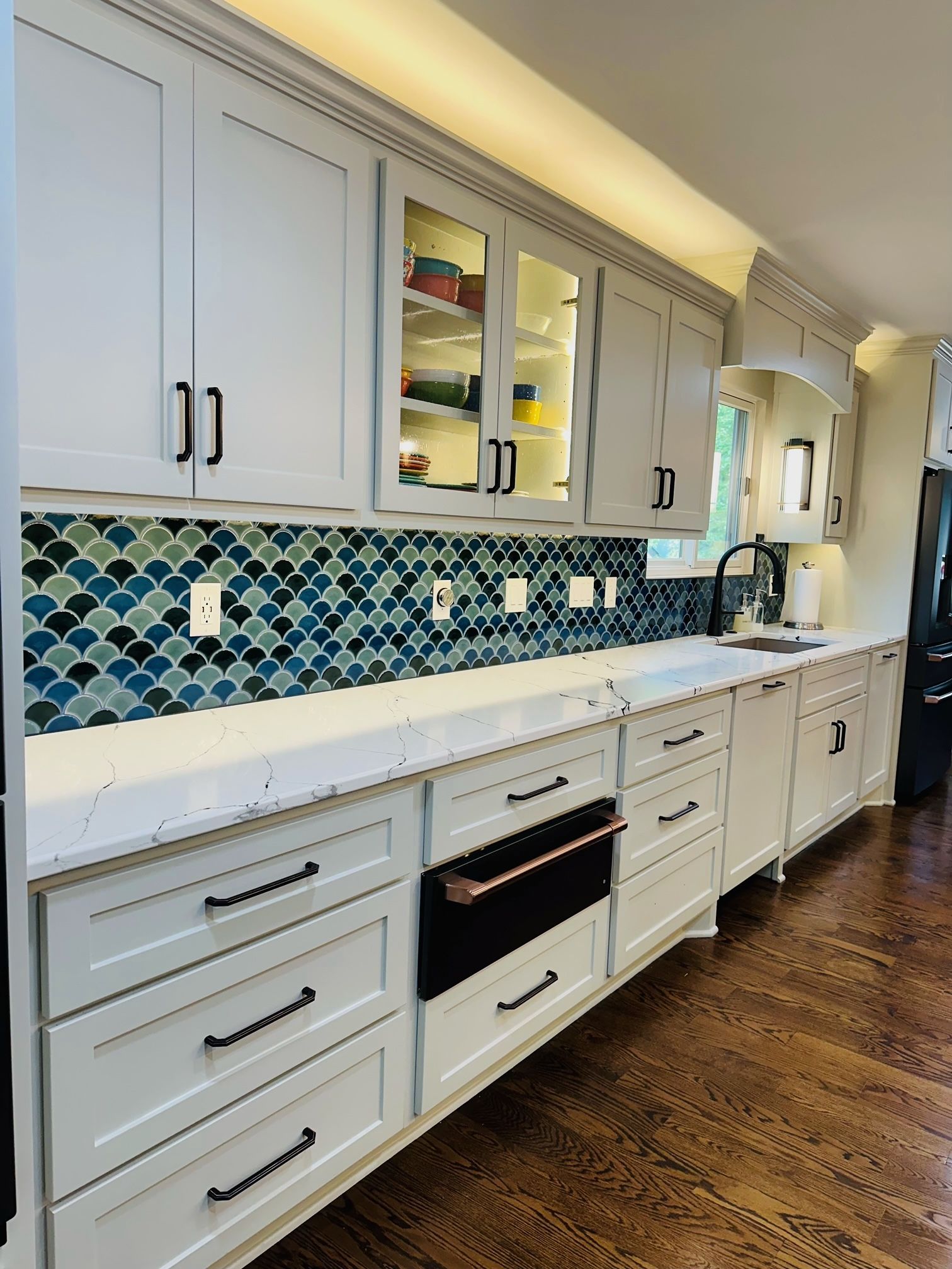 A kitchen with white cabinets and wooden floors