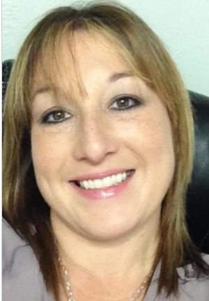 Smiling woman with light brown hair and a white top, facing the camera.