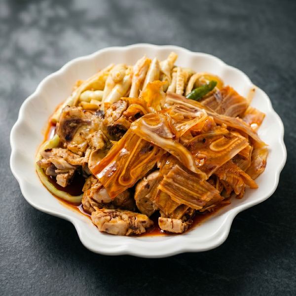 Steamed fish and tofu with red chili oil on a white scalloped plate