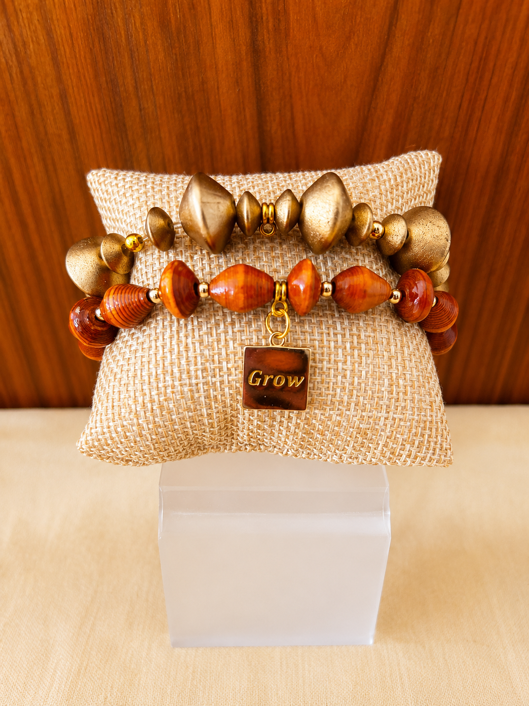 Beaded bracelet on burlap cushion with gold and amber stones against a wooden backdrop