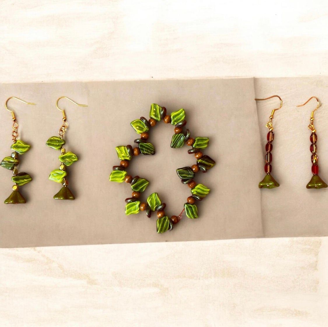 Green beaded jewelry set: matching earrings and a bracelet on beige fabric