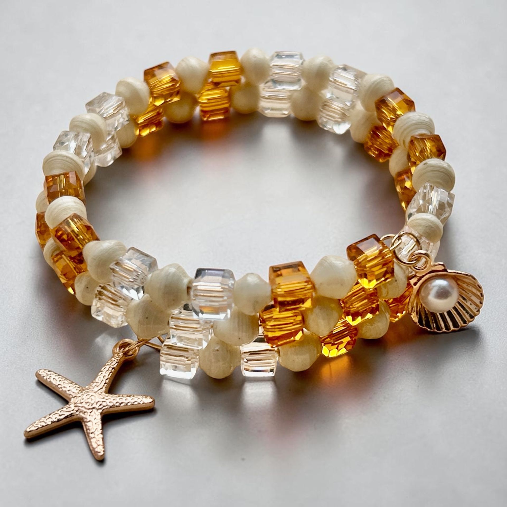 Clear and amber beaded bracelet with a starfish charm on a light surface