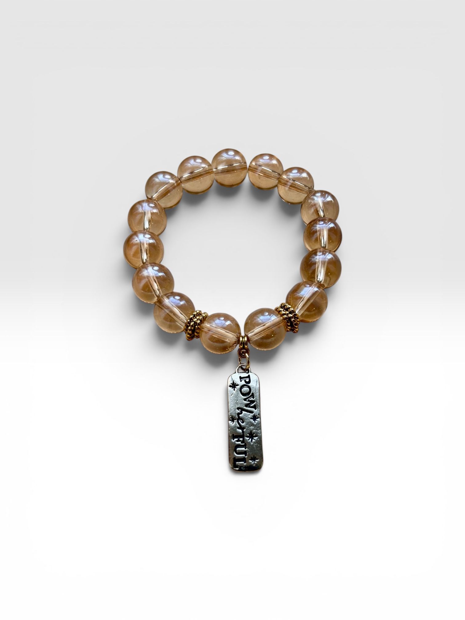 Amber beaded bracelet with a dangling black charm on a white background