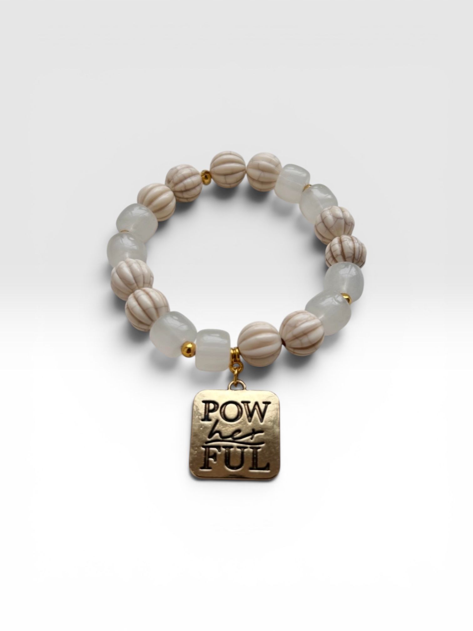 Beaded bracelet with gold “POWERFUL” charm on a white background