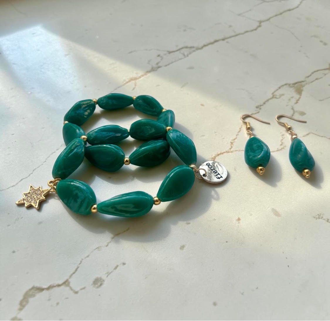 Teal bead necklace and matching earrings on a light marble surface