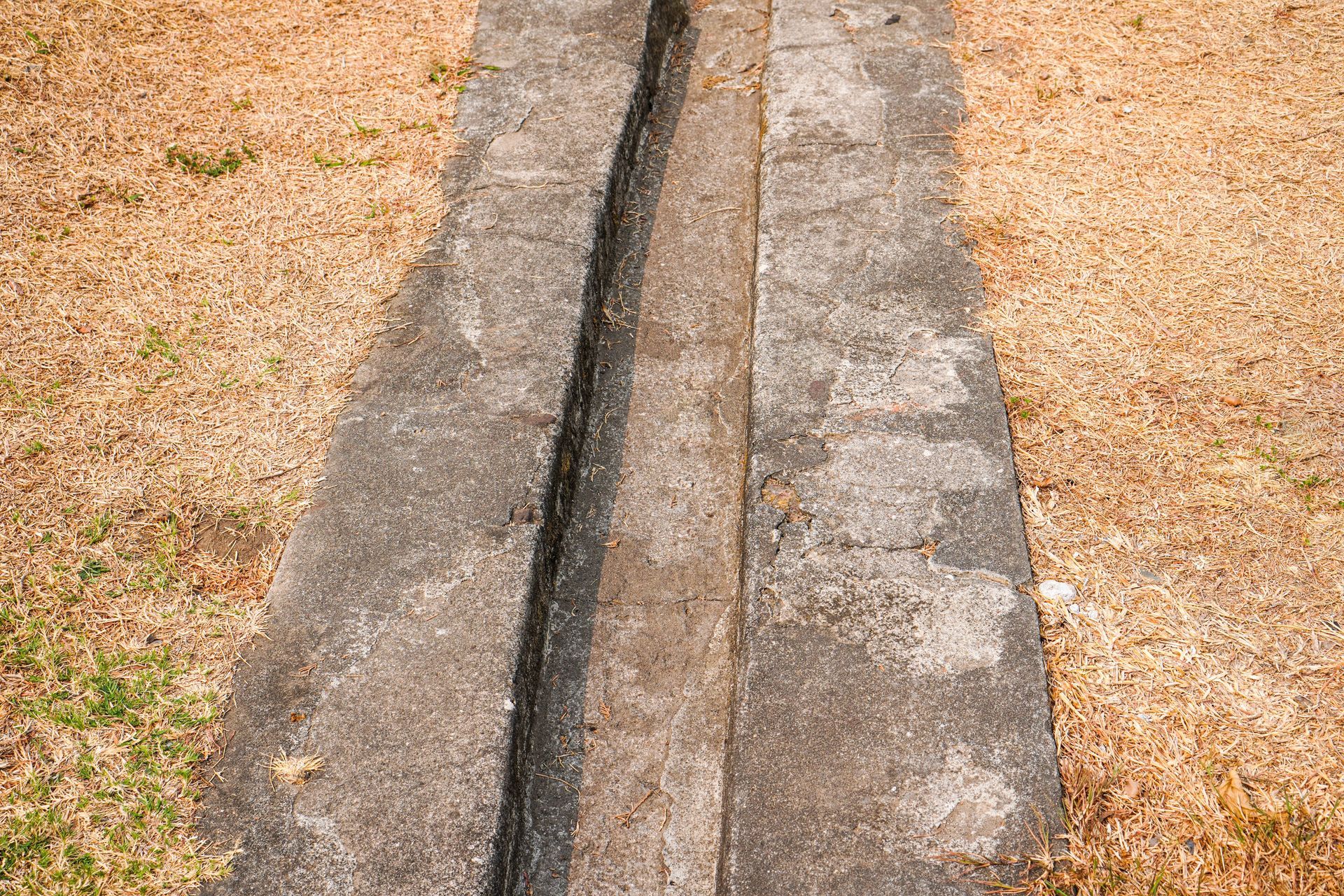 Concrete drainage channel running through gravel ground